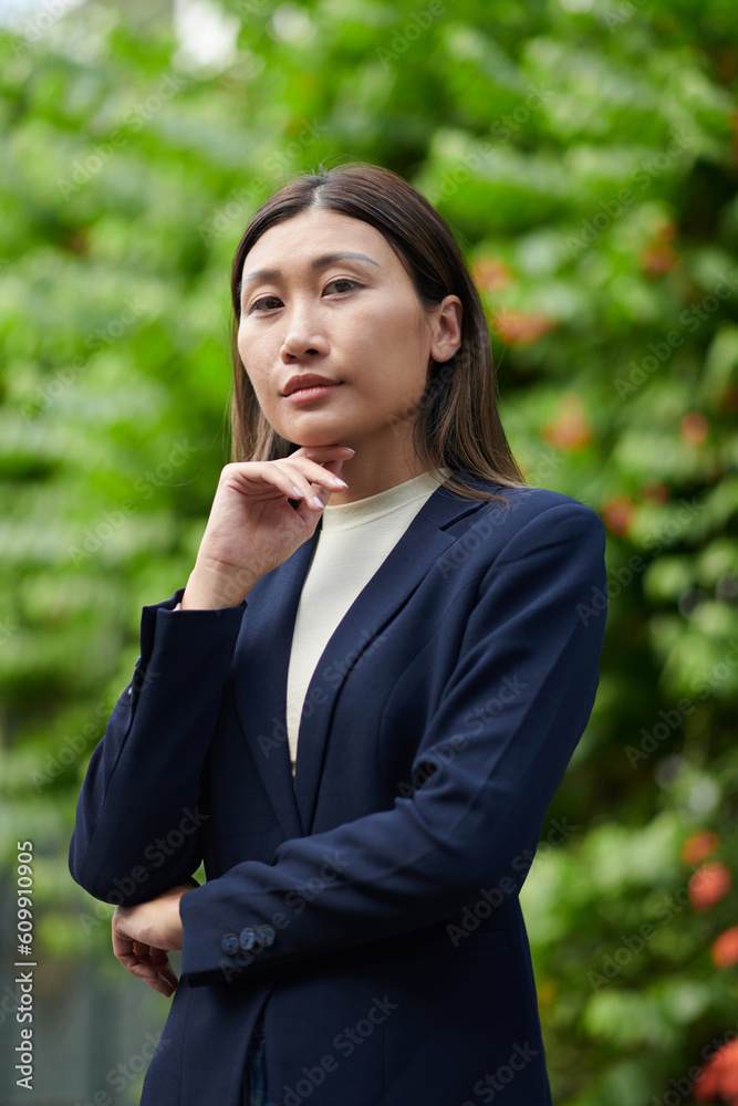 Confident successful businesswoman standing outdoors and looking down at camera Confident successful businesswoman standing outdoors and looking down at camera