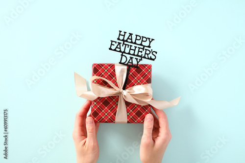 Woman's hands holding vintage Fathers Day gift box over blue background.