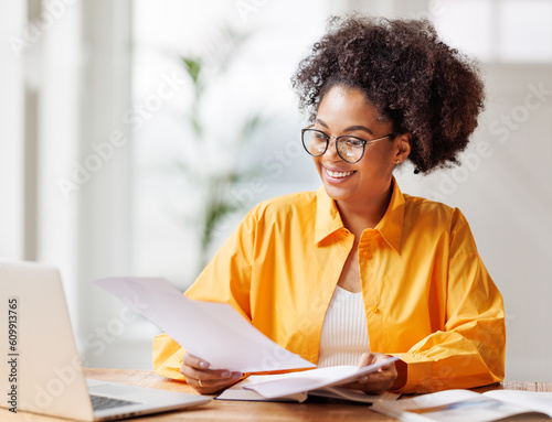 beautiful young smiling ethnic woman working remotely behind laptop at home