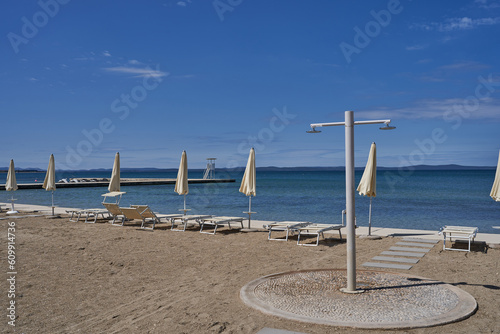  Zaton, Croatia - May 18, 2023 - the sea beach with sunshades in Zaton on the morning of a sunny spring day 