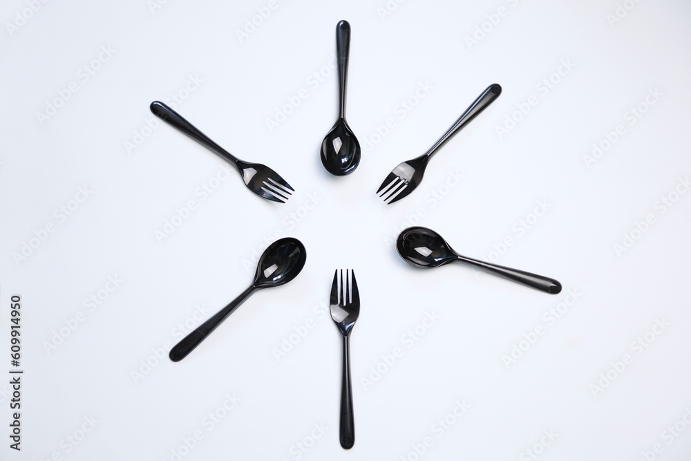 Top view composition of black plastic forks and spoons placed on white background Top view composition of black plastic forks and spoons placed on white background