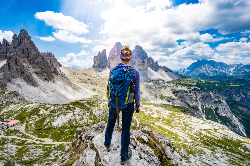 Fototapeta premium Young athletic woman enjoys view on Monte Paterno and Tre Cime at noon. Tre Cime, Dolomites, South Tirol, Italy, Europe.