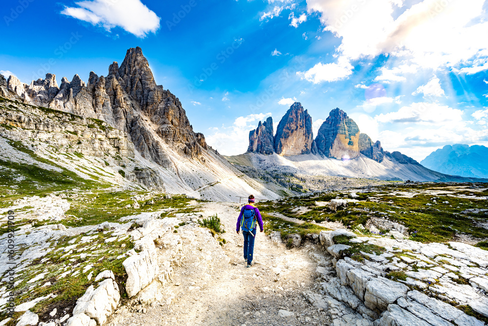 Young sportive woman walks on scenic hike trail at Tre Cime in the afternoon. Tre Cime, Dolomites, South Tirol, Italy, Europe. Young sportive woman walks on scenic hike trail at Tre Cime in the afternoon. Tre Cime, Dolomites, South Tirol, Italy, Europe.