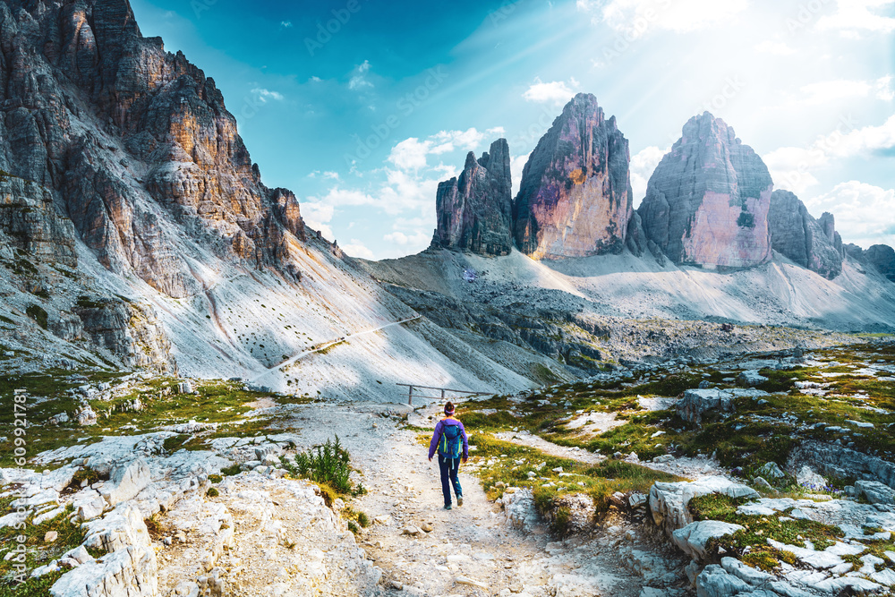 Young sportive woman walks on scenic hike trail at Tre Cime in the afternoon. Tre Cime, Dolomites, South Tirol, Italy, Europe.