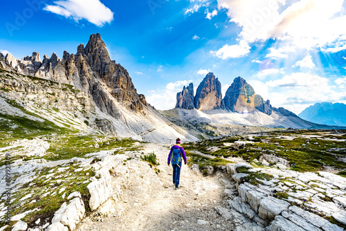 Young sportive woman walks on scenic hike trail at Tre Cime in the afternoon. Tre Cime, Dolomites, South Tirol, Italy, Europe.