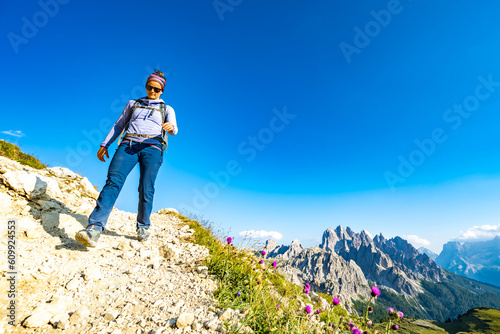 Young sportive woman walks along scenic Dolomites high trail in the evening. Tre Cime, Dolomites, South Tirol, Italy, Europe.