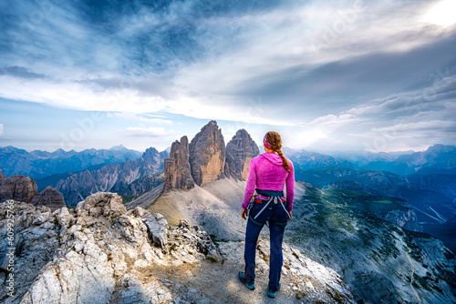 Young athletic woman enjoys summit view on Tre Cime from Paternkofel in the evening. Tre Cime, Dolomites, South Tirol, Italy, Europe.