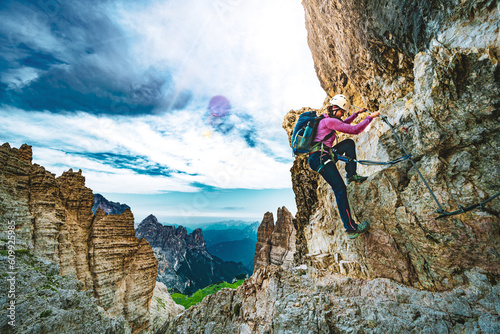 Young athletic woman hikes in via ferrata in the evening. Tre Cime, Dolomites, South Tirol, Italy, Europe. photo