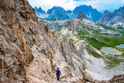 Young athletic woman enjoys view on Drei-Zinnen-Hütte from via ferrata in the evening. Tre Cime, Dolomites, South Tirol, Italy, Europe.