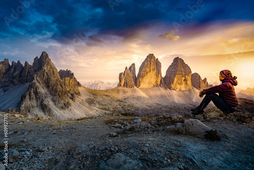 Sportive woman enjoys epic view from Sextner Stein on Monte Paterno and Tre Cime mountain range in the evening. Tre Cime, Dolomites, South Tirol, Italy, Europe.