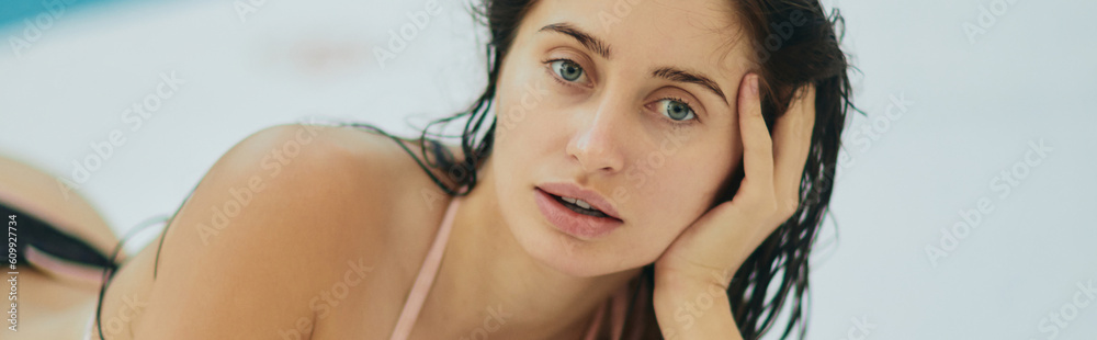 brunette woman in bikini, sexy model with wet hair posing in luxury resort, Miami, Florida, USA, blurred background, laying down on white surface, poolside relaxation, looking at camera, banner brunette woman in bikini, sexy model with wet hair posing in luxury resort, Miami, Florida, USA, blurred background, laying down on white surface, poolside relaxation, looking at camera, banner