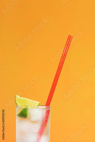Iced tea with ice and lime on an orange background. Summer cocktail with cold drink. Copy space