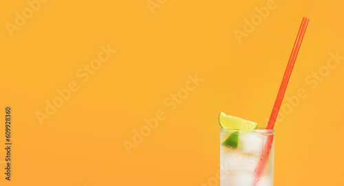 Iced tea with ice and lime on an orange background. Summer cocktail with cold drink. Copy space