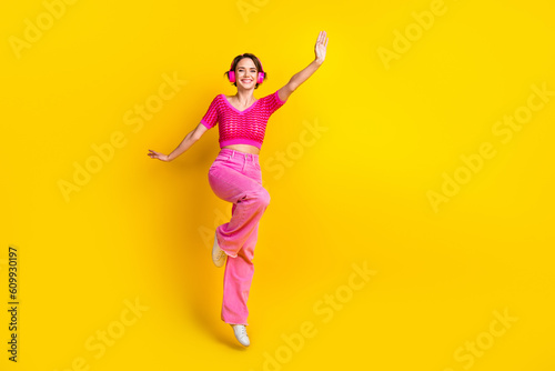 Full size photo of good mood girl wear knit top pink pants having fun listening playlist dancing isolated on yellow color background