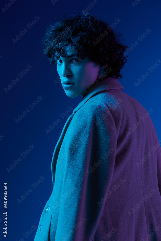 Man portrait in coat fashion on dark blue background, neon light, style and trends, mixed light, men's fashion, copy place Man portrait in coat fashion on dark blue background, neon light, style and trends, mixed light, men's fashion, copy place