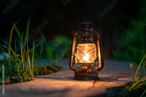 the antique oil lamp on the old wooden floor in the forest at night camping atmosphere