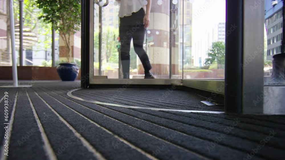 Low angle of feet passing through revolving doors of a building