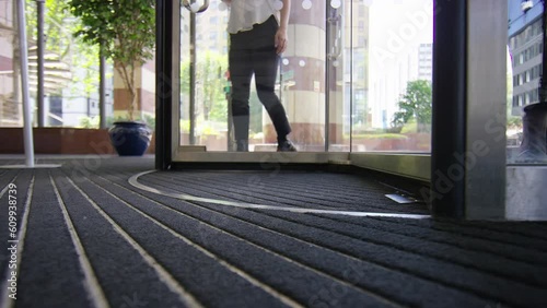 Low angle of feet passing through revolving doors of a building