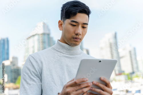 Portrait of asian man holding digital tablet, working outdoors. Chinese businessman online shopping