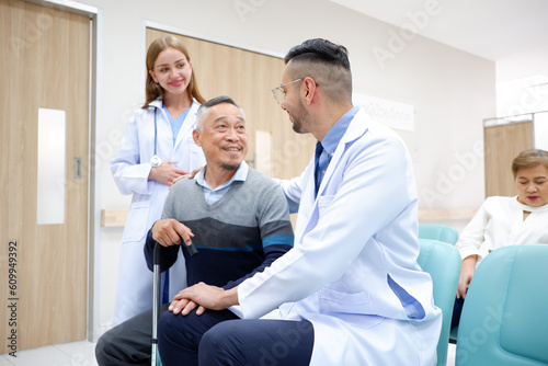 A doctor caring for and consulting an old male patient with a smile of encouragement.