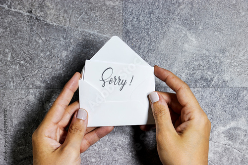 Photos woman hand holding a white envelope with sorry concept on gray grunge background
