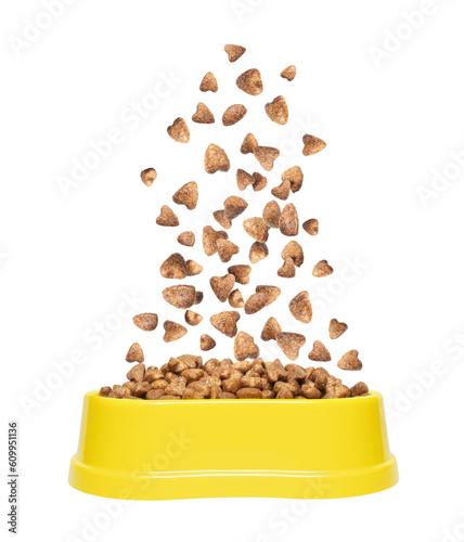 Dry food for cats or dogs falls in a yellow plastic bowl isolated on a white background