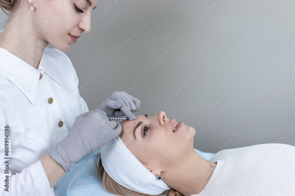 Fototapeta premium A doctor gives an injection of hyaluronic acid to a young woman