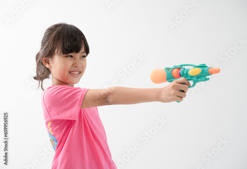 Happy Songkran Day, Asian kid girl hold water gun, Thai child funny hold toy water pistol and smile, isolated on white background, Thailand Songkran festival national culture concept photo