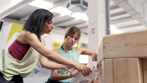 Women using touchscreen to change angle of kilter board