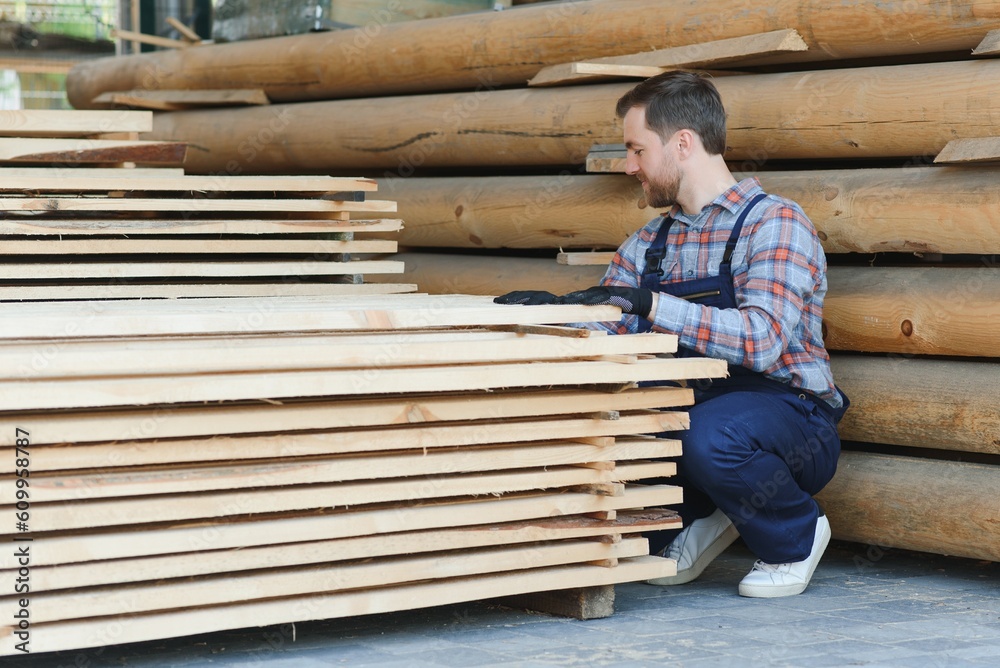 Industrial warehouse of a sawmill, an employee puts his hands on the finished products at the sawmill in the open air. Industrial warehouse of a sawmill, an employee puts his hands on the finished products at the sawmill in the open air.