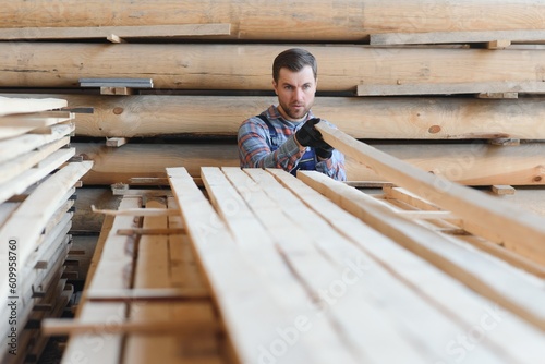 Timber harvesting for construction. Carpenter stacks boards. Industrial background. Authentic workflow.