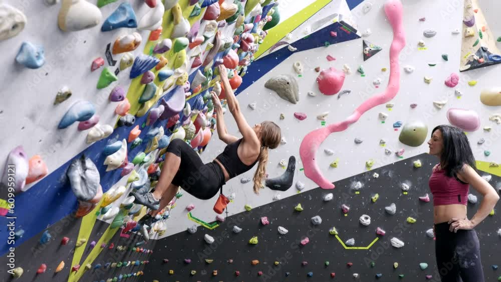 Women climbing bouldering wall with colorful grips