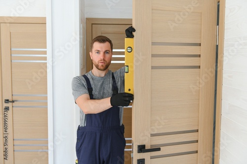 Wallpaper Mural handsome young man installing a door in a new house construction site. Torontodigital.ca