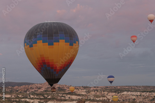 Colorful air balloons float in sky over mountain valley