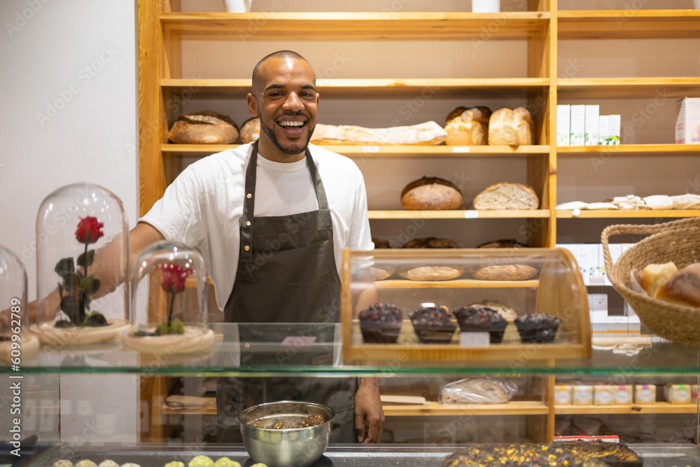 Positive black man standing at counter in bakery Positive black man standing at counter in bakery