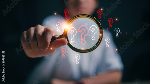 The concept of finding an answer to complex questions in business. Hand holding a magnifying glass with a question mark.