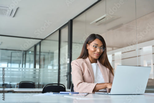 Busy professional business woman employee working looking at computer typing in office. Young African American female company finance manager executive using laptop sitting at desk. Copy space