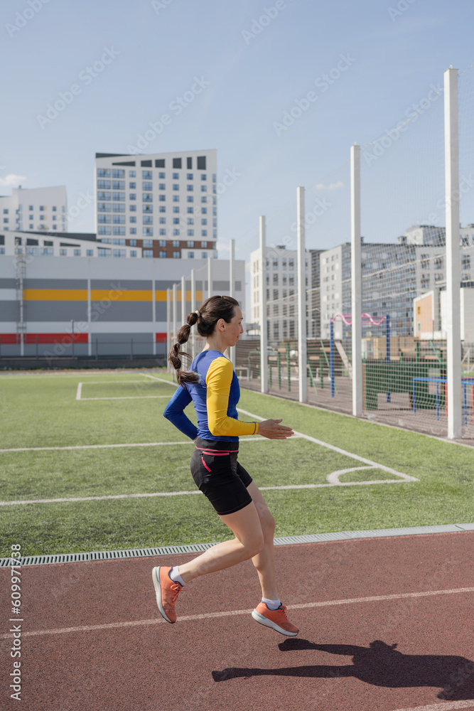 Running young woman in sportswear on stadium