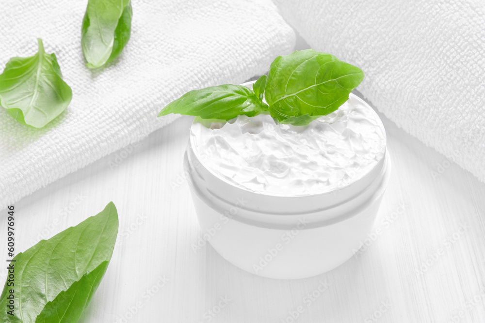 Pure white moisturizer in a white jar. White towel. Green leaves. Pure white moisturizer in a white jar. White towel. Green leaves.