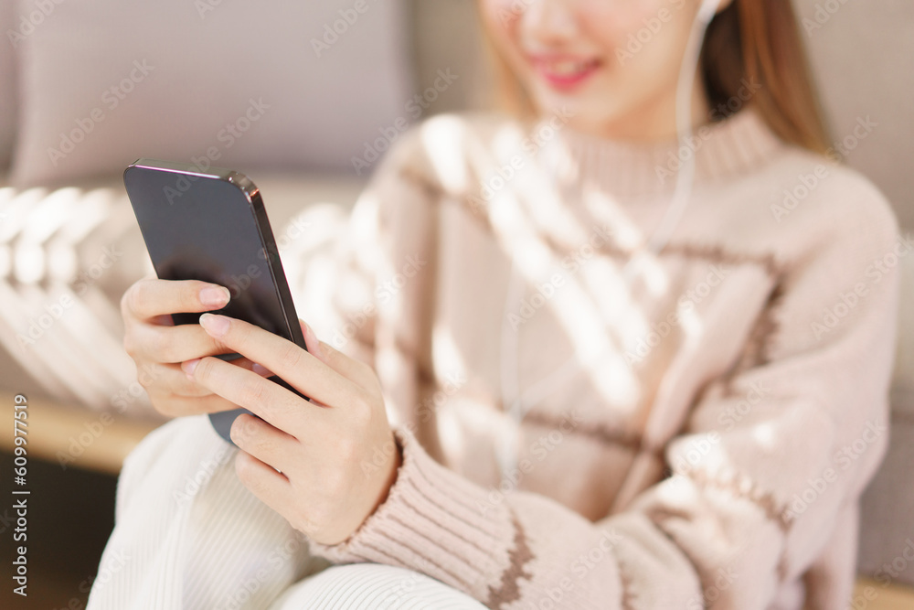 Leisure time concept, Women sitting on floor and wearing earphone to watching movie on smartphone Leisure time concept, Women sitting on floor and wearing earphone to watching movie on smartphone