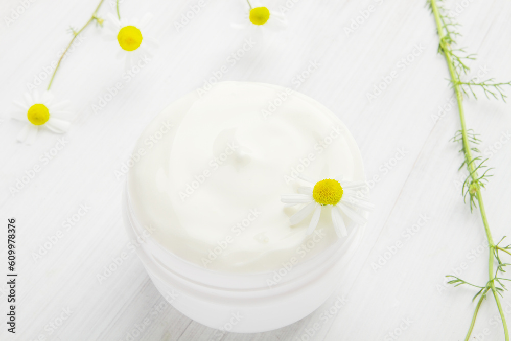 White nourishing cream with chamomile in a white jar. White nourishing cream with chamomile in a white jar.