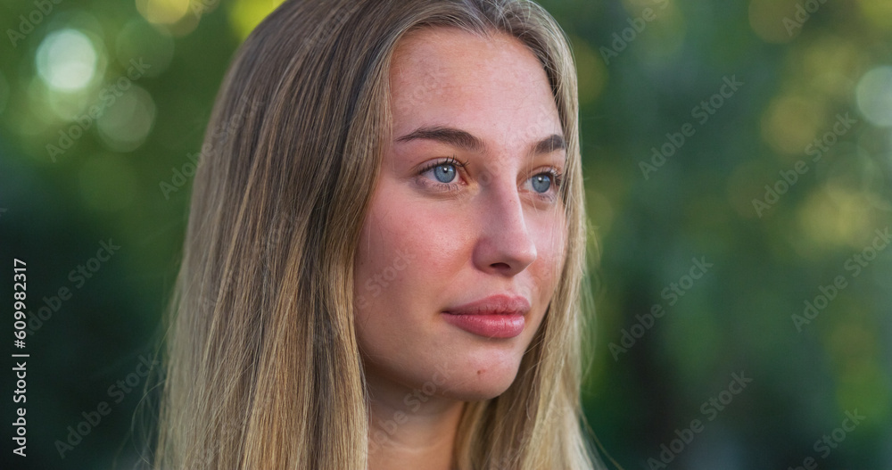 Fototapeta premium Portrait of Beautiful Caucasian Young Woman Smiling with a Greenery Background. Happy Blond Female Teenager Enjoying Fresh Air in the Park and Taking Care of her Wellbeing