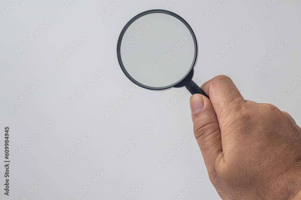 hand holding a magnifying glass on a white background hand holding a magnifying glass on a white background