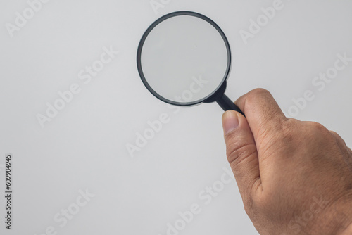 hand holding a magnifying glass on a white background