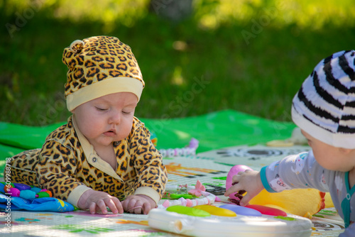 A child plays with toys on a green lawn. Little girl in leopard costume.