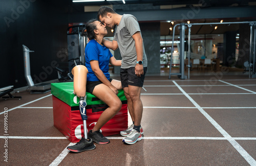 Woman with prosthetic leg and husband take care at fitness or gym 