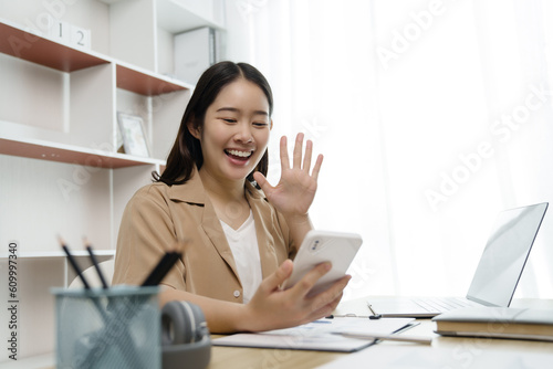 Happy asian woman using mobile phone for video conference at home.