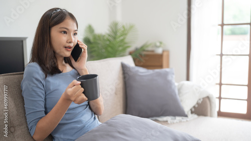 Happy young asian woman using mobile phone talking with friends on cell phone
