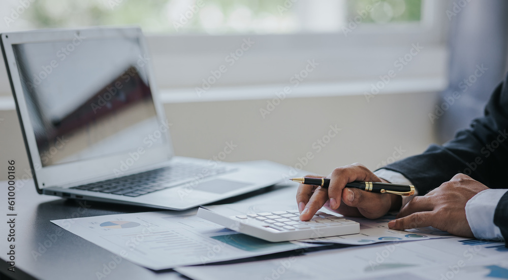 Fototapeta premium Close up work of businessman or accountant using calculator and laptop while analyzing business report in workplace financial planning and accounting concept