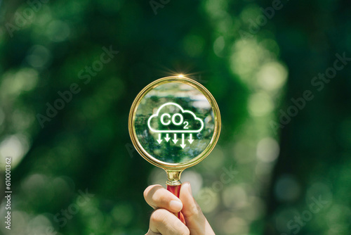 hand holding magnifying glass with CO2 reduction icon inside.A clean and friendly environment without carbon dioxide emissions.carbon credit to limit global warming from climate change.carbon neutral.